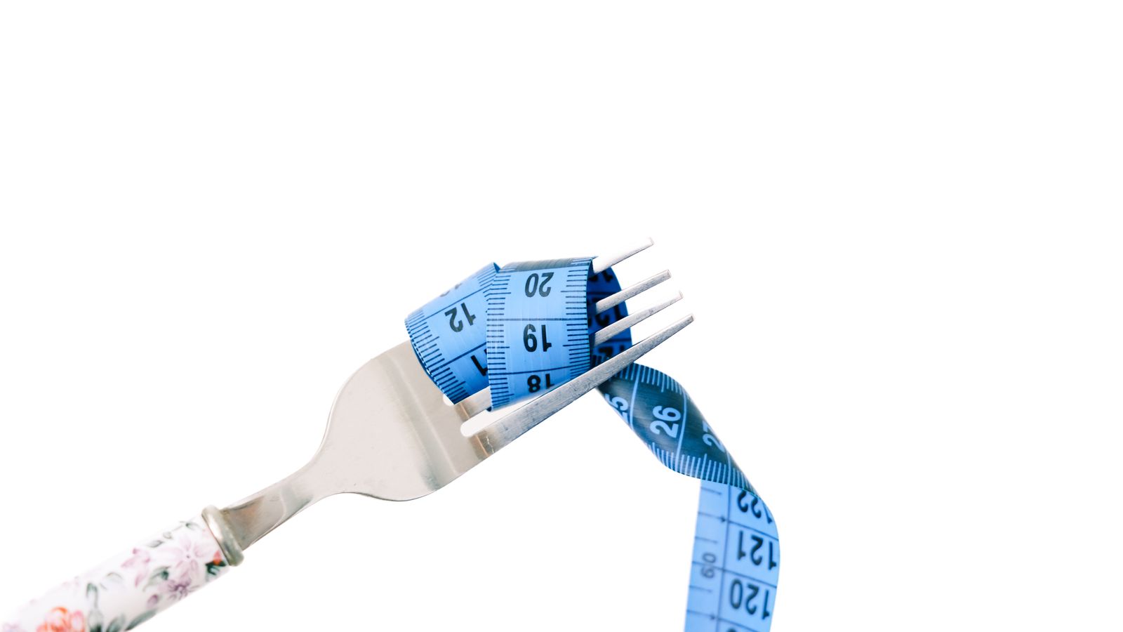 Tenedor con cinta metrica azul sobre fondo blanco, imagen editorial sobre perdida de peso.