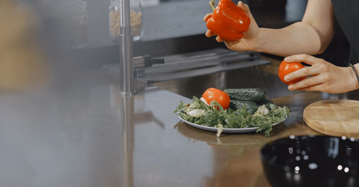 A person preparing fresh vegetables in a modern kitchen setting.