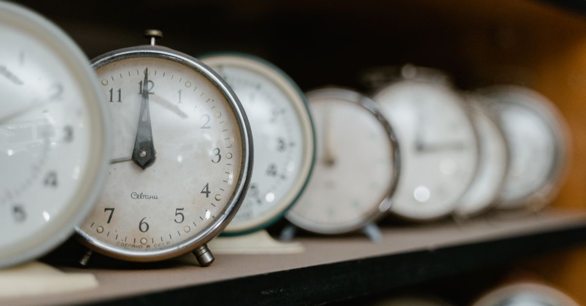 A collection of vintage analogue alarm clocks arranged on a wooden shelf.