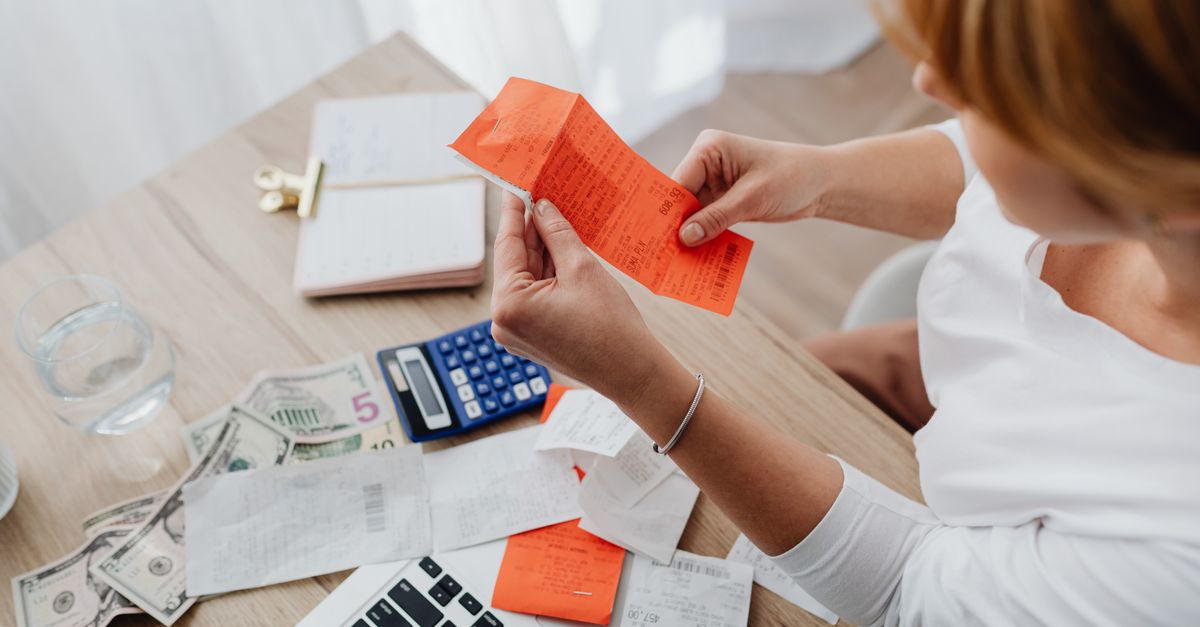 Woman using calculator and receipts at home office desk for finance management.