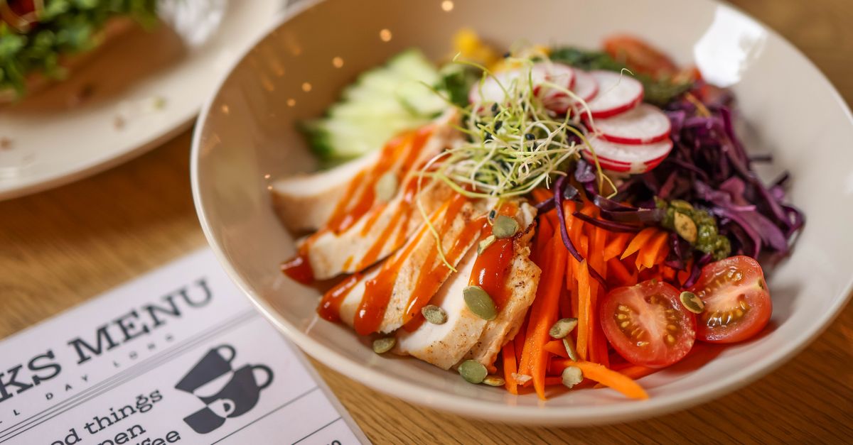 A vibrant salad bowl featuring fresh vegetables and grilled chicken on a wooden table.