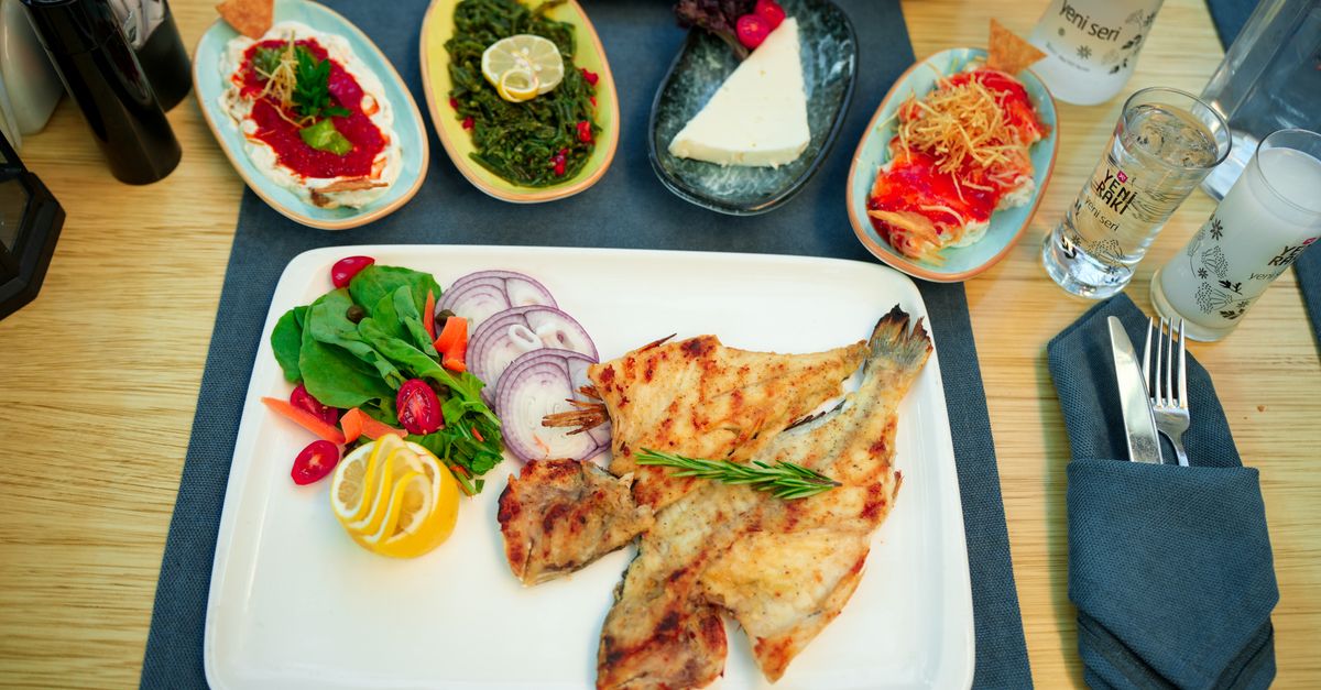 Delicious Mediterranean meal featuring grilled fish, fresh salad, and traditional sides.