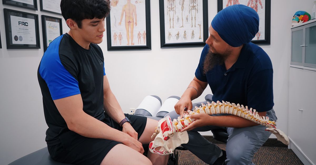 A doctor explains spinal issues to a patient using a spine model during a medical consultation.