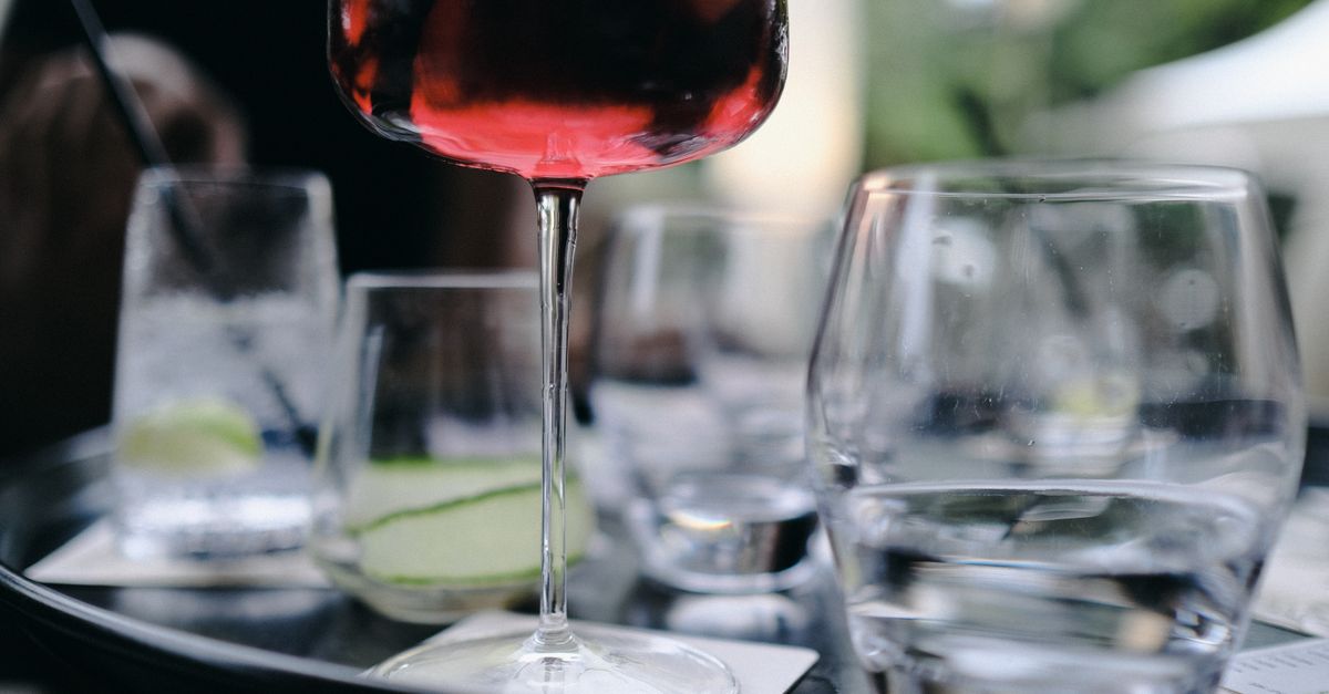 Close-up of red wine glass amidst elegant dining setup, perfect for luxury vibes.