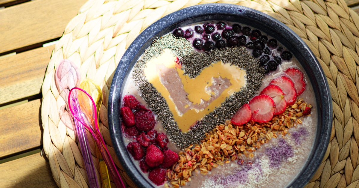 Colorful smoothie bowl with berries, chia seeds, and a heart of peanut butter for a healthy breakfast.