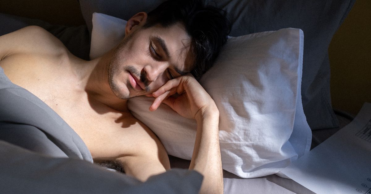 A man peacefully sleeping in a sunlit bedroom with natural light streaming in.