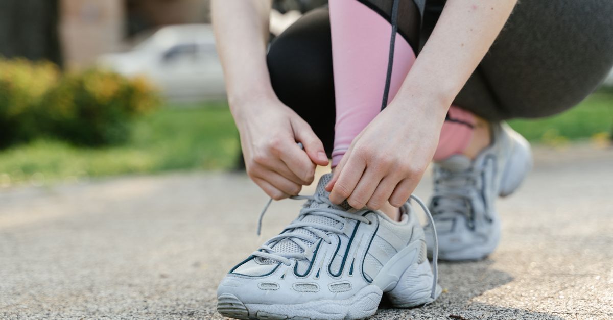 Woman tying shoelaces on sneakers before a run in the park.