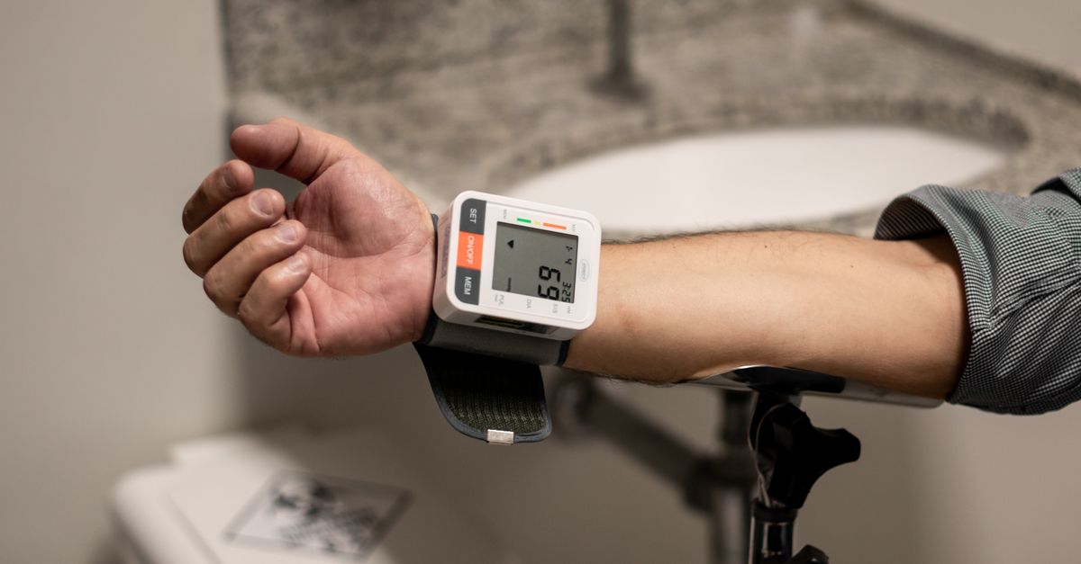 Close-up of an arm using a wrist sphygmomanometer in a healthcare setting.