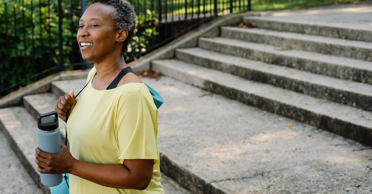 Senior woman exercising outdoors, smiling, holding a water bottle. Perfect for lifestyle and fitness themes.