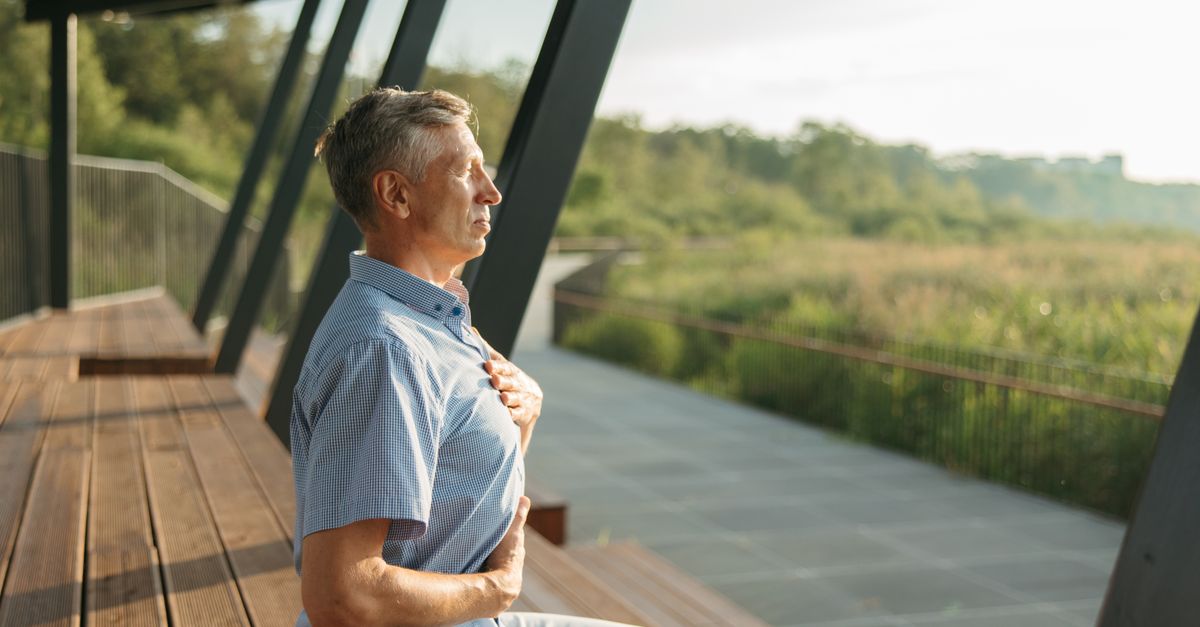 Senior man practicing meditation outdoors, embracing peaceful relaxation and mindfulness during daylight hours.