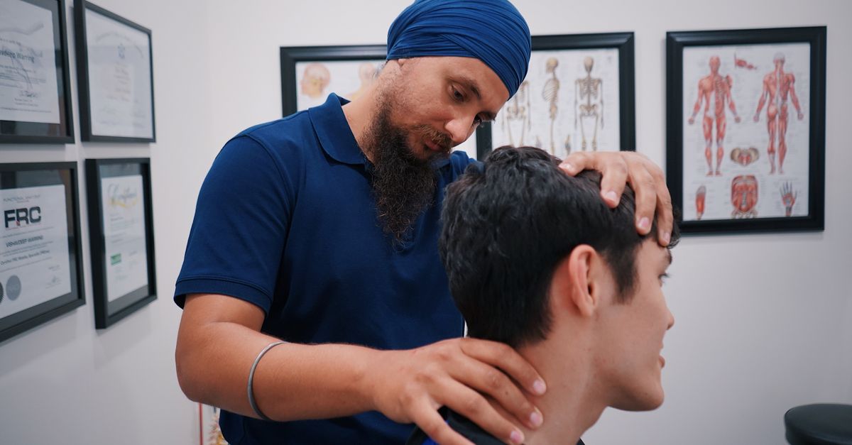 Professional physiotherapist adjusting a patient's neck in a medical office.