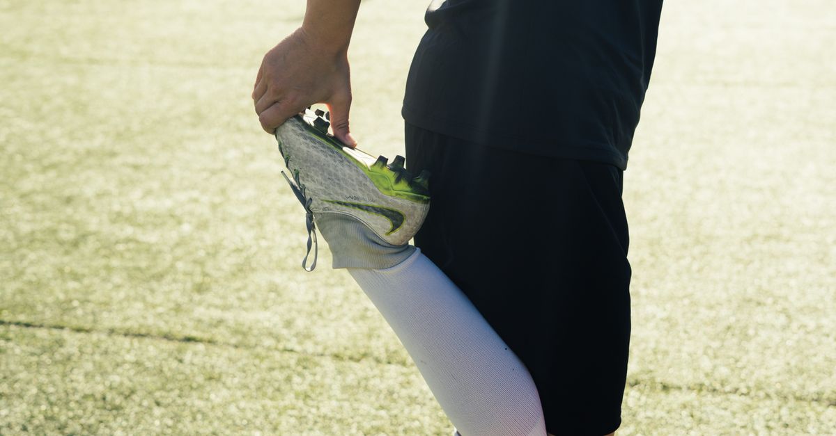 Athlete stretching before soccer practice on a sunny day outdoors.