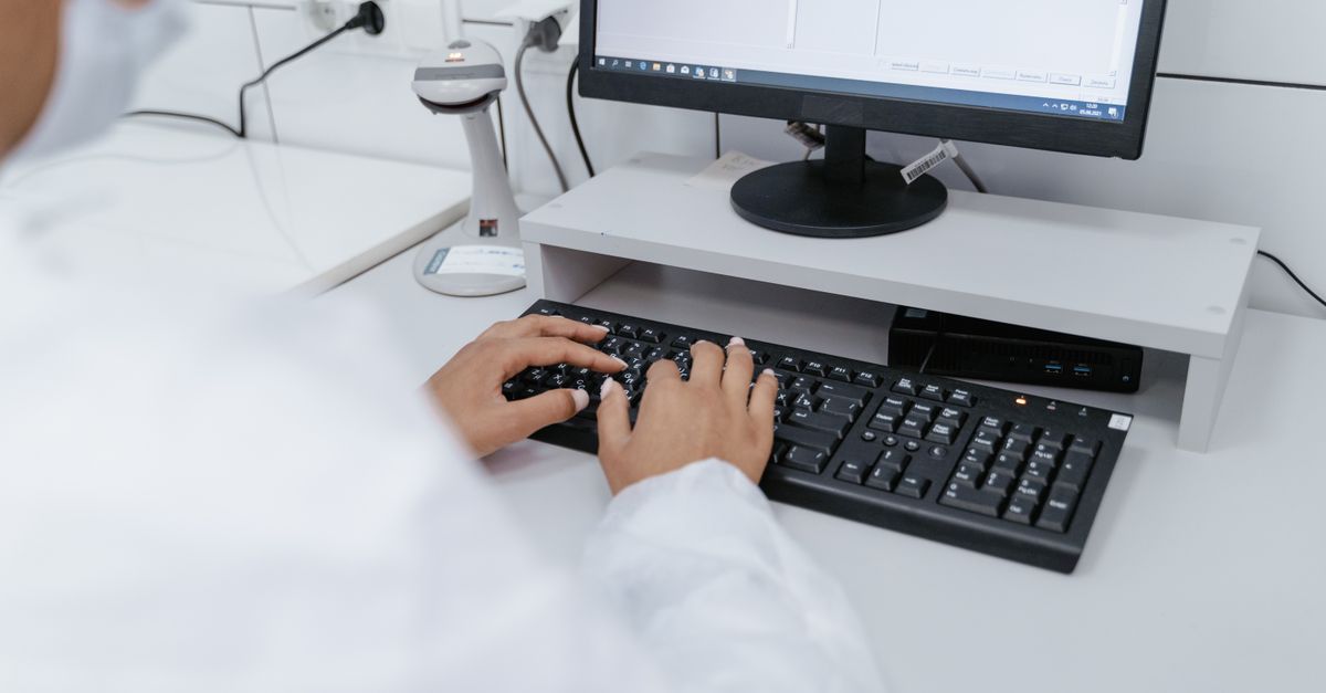 Scientist in white coat using a computer in a laboratory setting, focusing on data analysis.