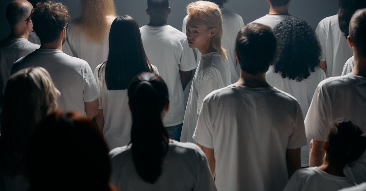 A diverse crowd stands together in a studio, exploring themes of individuality and social connections.