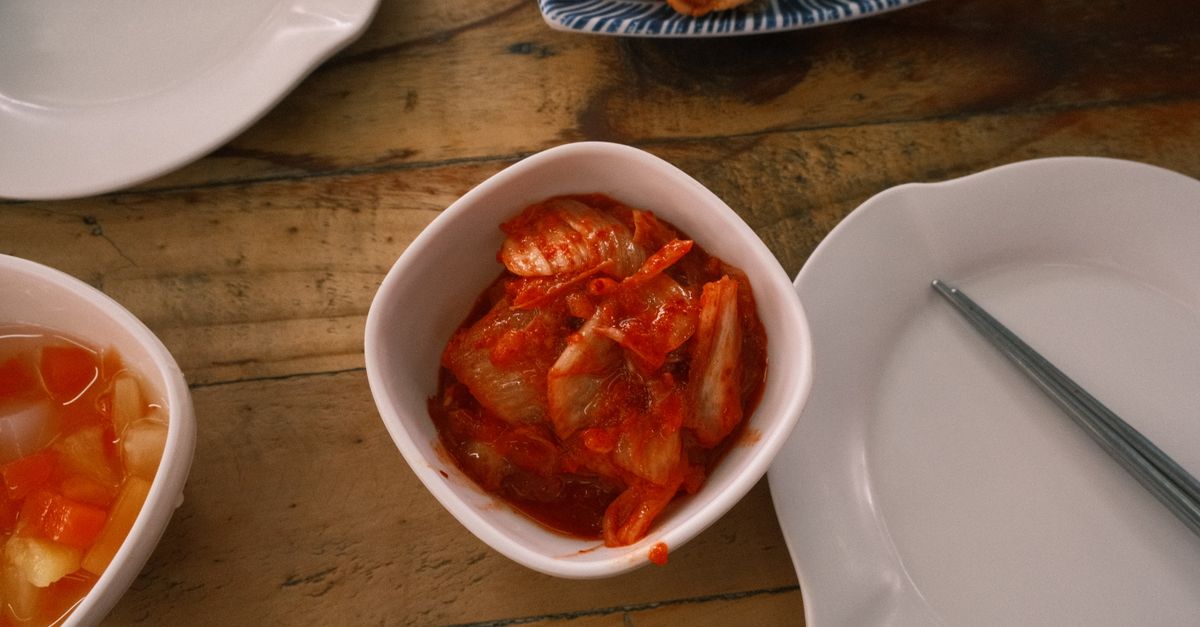 Top view of traditional Korean kimchi in a white bowl on a rustic wooden table.