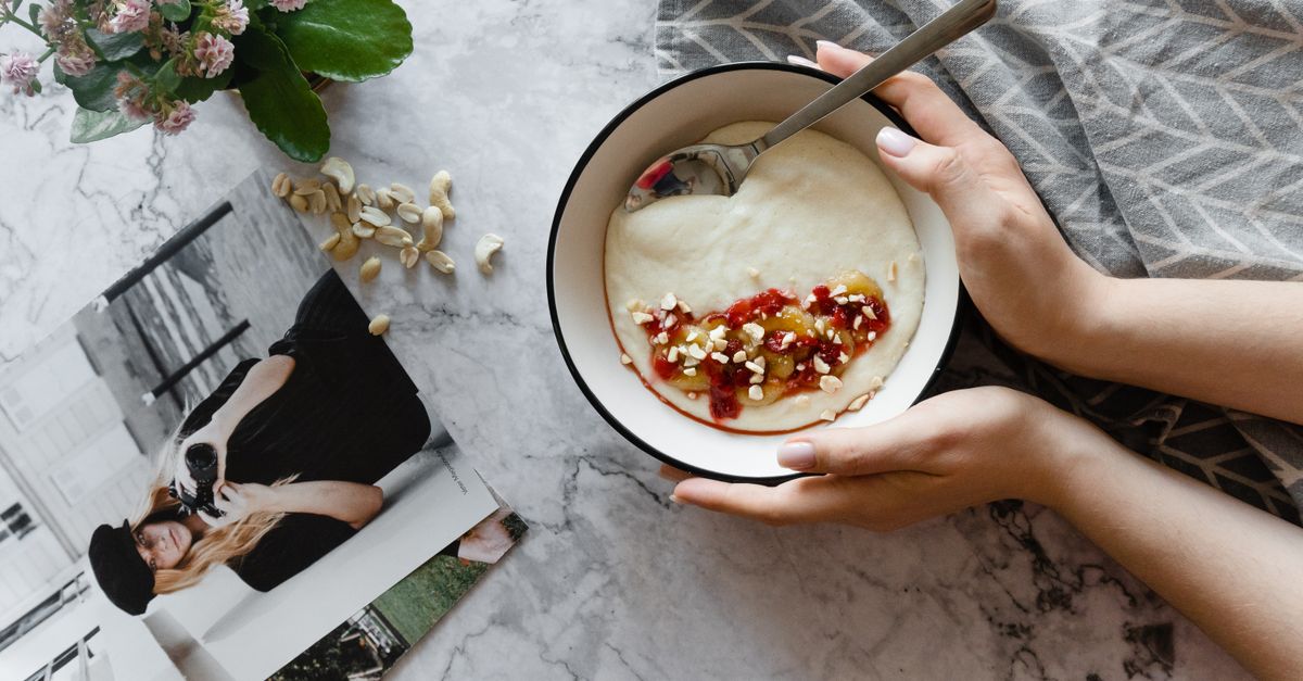 Top view of a yogurt bowl with nuts and berries on a marble table.