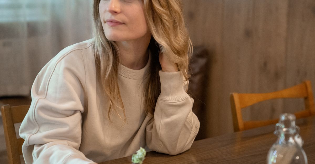 Caucasian woman enjoying a meal indoors, relaxed and smiling.