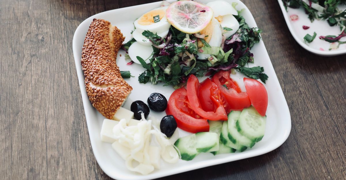 A vibrant Mediterranean breakfast featuring eggs, salad, cucumbers, tomatoes, and more on a plate.