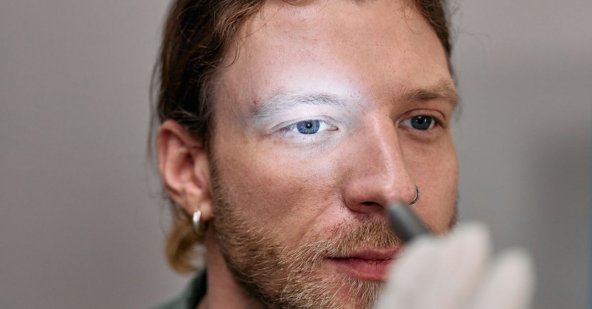 A close-up image of a young man undergoing an eye examination by a medical professional.