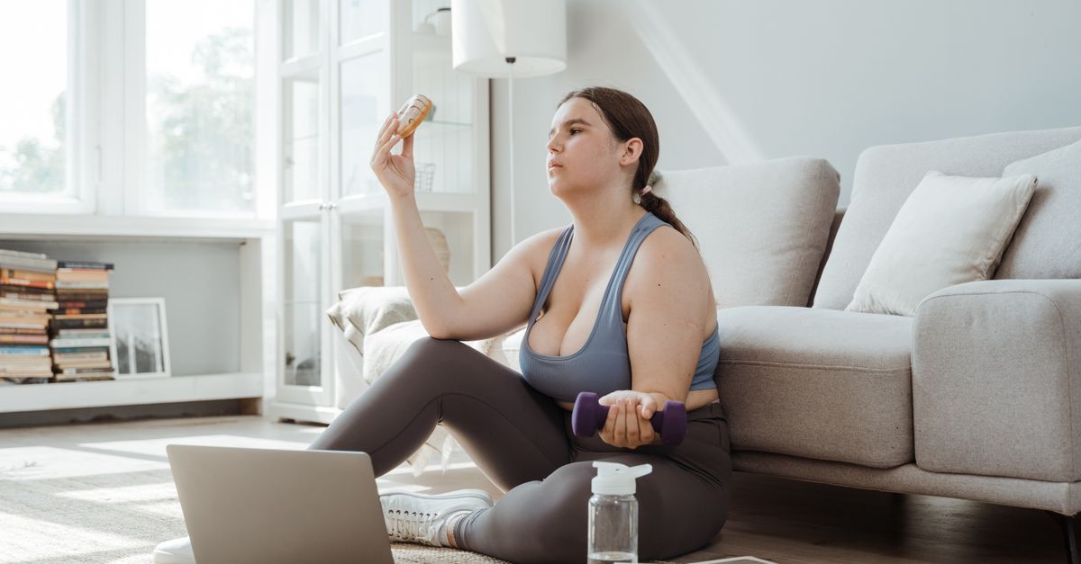 Plus-size woman exercising and making healthy choices in a cozy living room.