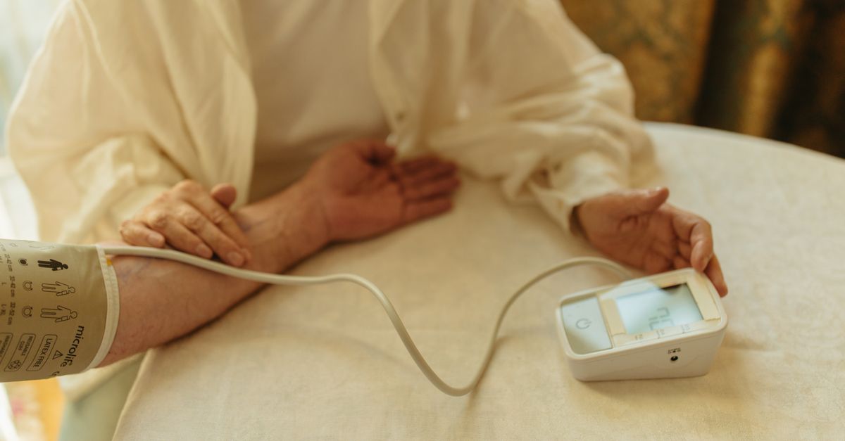 A senior adult checking their blood pressure with a digital monitor at home.