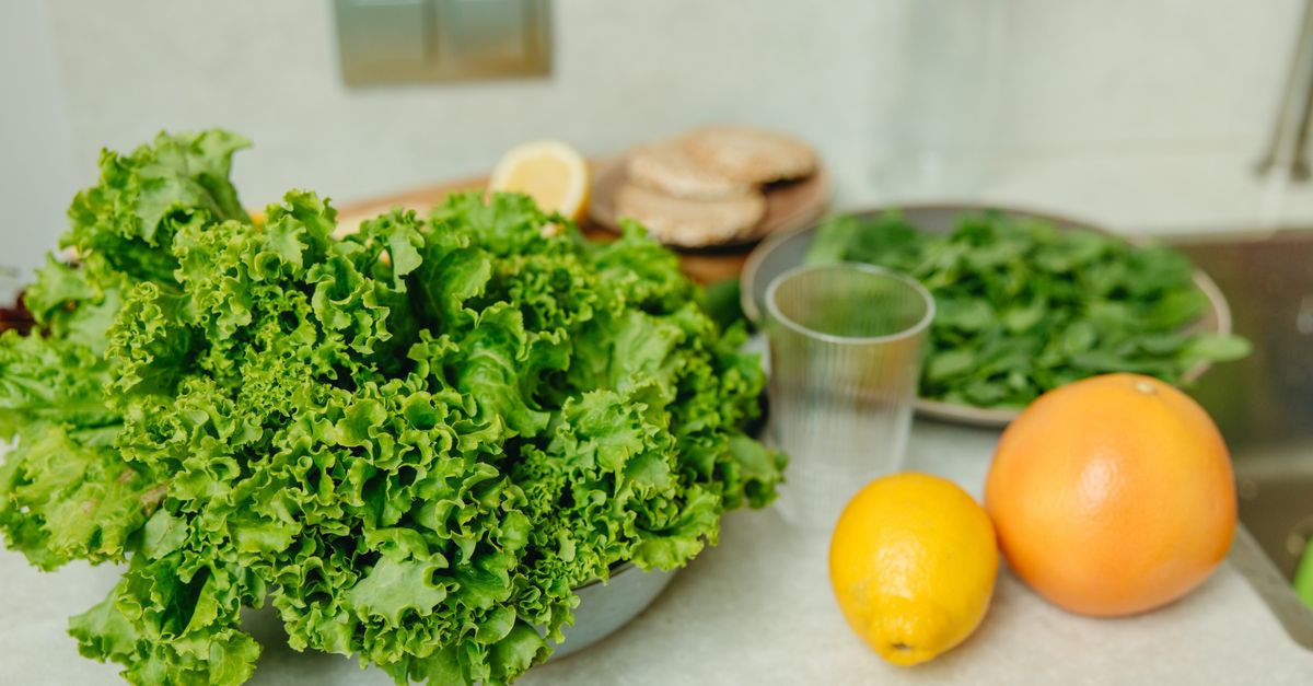 A vibrant display of fresh green lettuce and citrus fruits on a kitchen table.