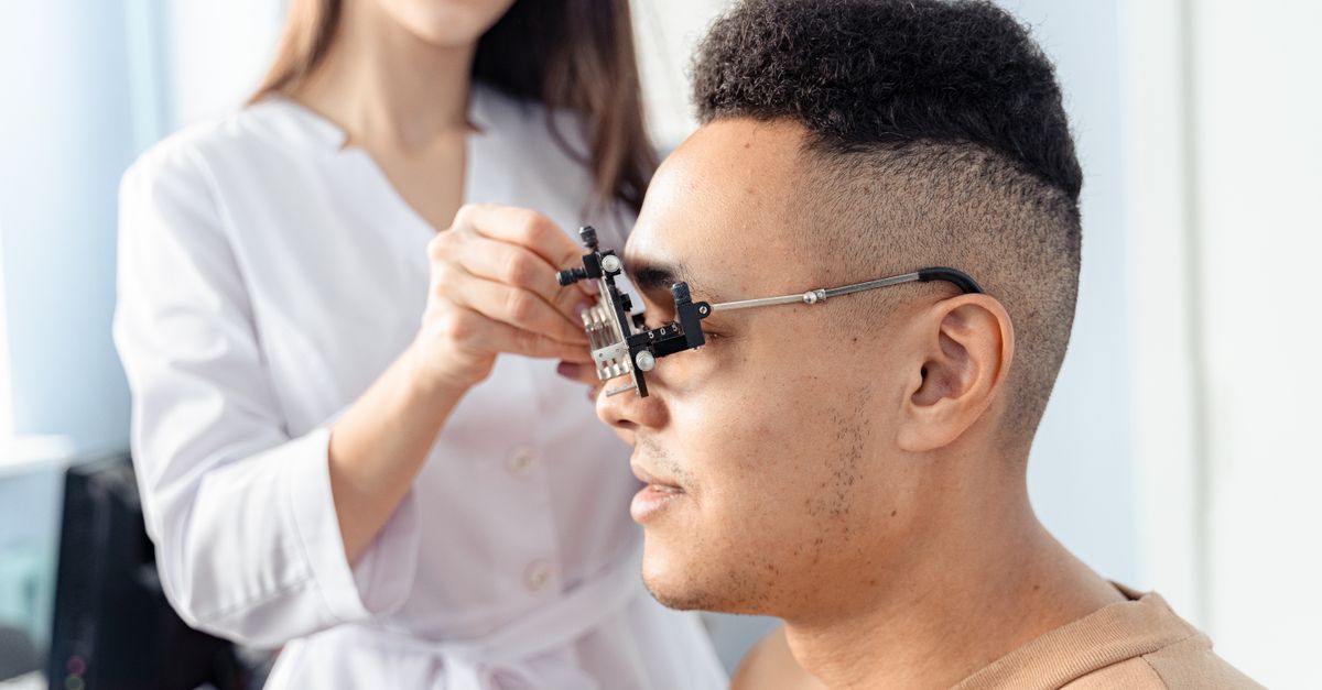 Side view of optometrist fitting trial frame on a patient during an eye exam.