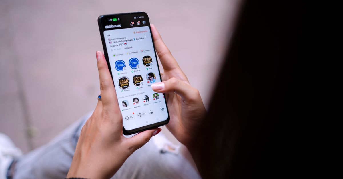 Close-up of a woman using a smartphone with social media app open. Hands holding device.