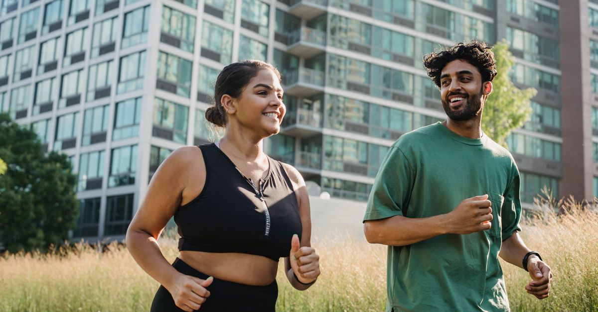 A joyful couple jogging in a city park, promoting a healthy lifestyle.