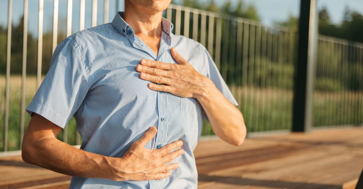A man practicing relaxation with hands on chest and abdomen outdoors.