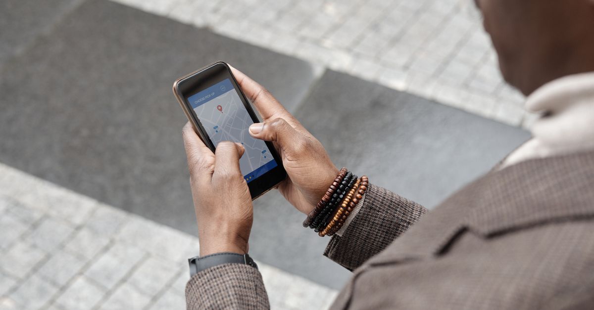 A stylish professional adult using a smartphone with a navigation app on an urban street.