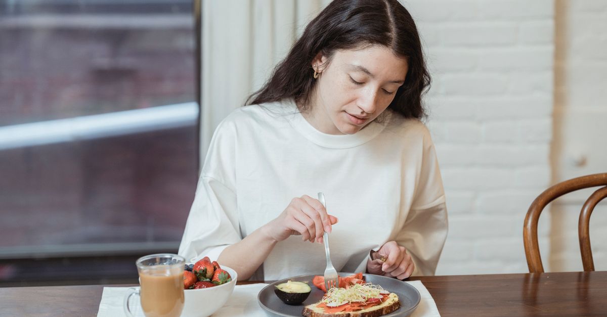 Woman having a nutritious breakfast with toast and strawberries in a cozy indoor setting.