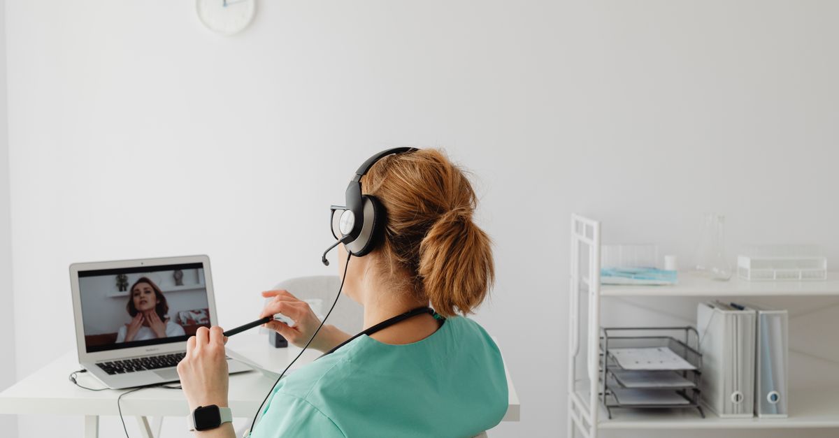 Medical professional conducting an online consultation via video call in a modern office environment.